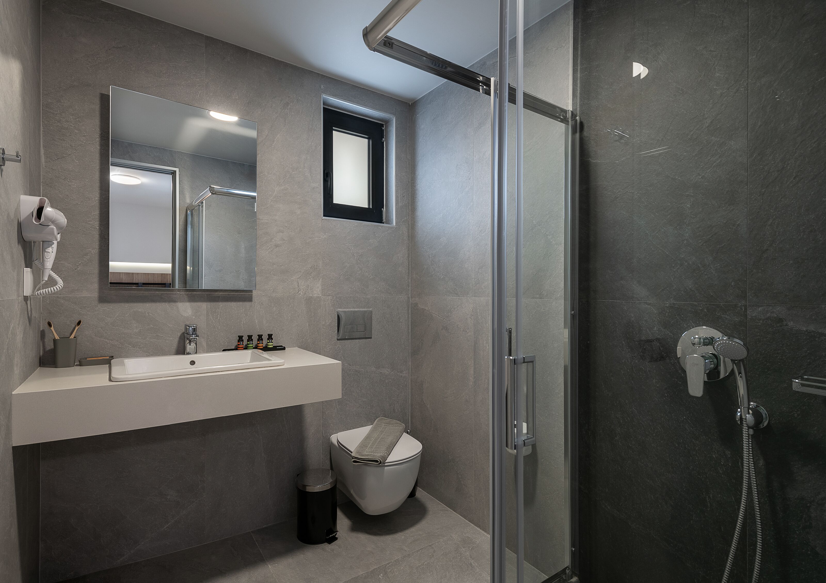 A modern bathroom with a glass-enclosed shower, a white sink, and a toilet.