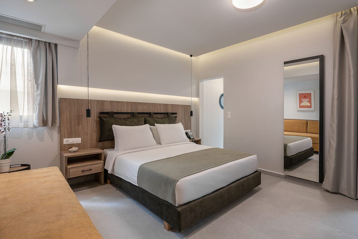 Ein modernes Schlafzimmer mit einem großen Bett, Nachttischen, einer Nachttischlampe, einem Spiegel und einer Topfpflanze.