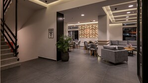 Een moderne hotel lobby met een trap, zithoek en een wand met een visgraatmotief.