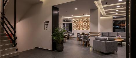 Een moderne hotel lobby met een trap, zithoek en een wand met een visgraatmotief.