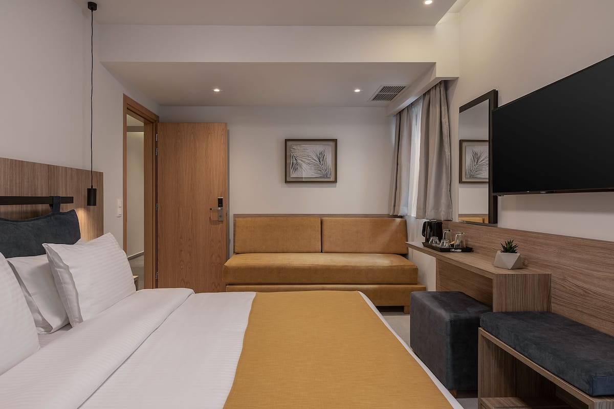 Ein modernes Hotelzimmer mit einem großen Bett, einer Couch, einem Schreibtisch und einem Flachbildfernseher.
