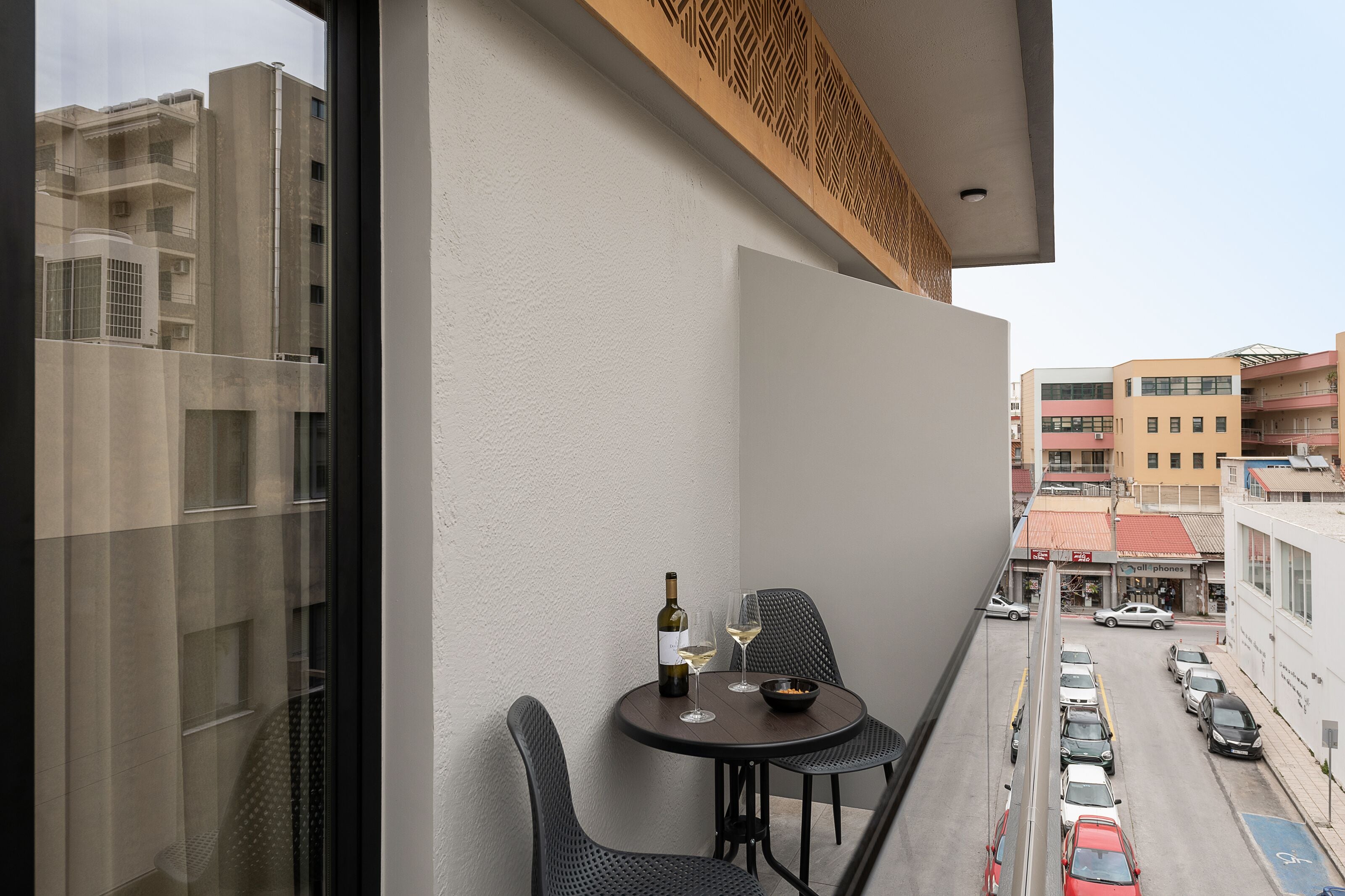 Een balkon met een tafel, twee stoelen, een fles wijn en een schaal met snacks.