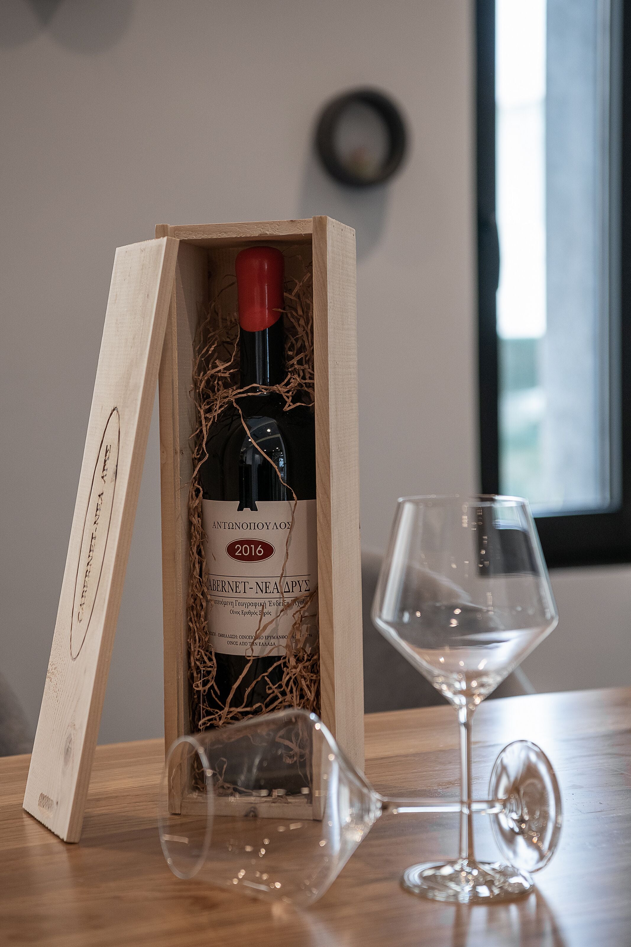 A wooden wine box with a bottle and a wine glass on a table.