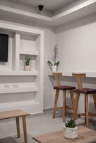 A modern room with white walls, a mounted TV, wooden chairs, and a small table.