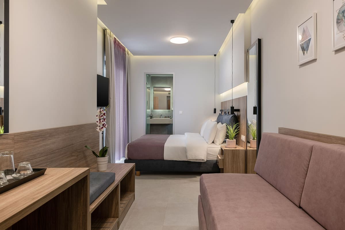 Ein kleines Hotelzimmer mit Bett, Sofa, Schreibtisch und einem Tisch.