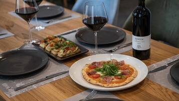 A dining table with two plates of pizza, wine glasses, and a bottle of wine.