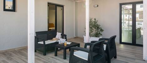 An outdoor patio area with wicker furniture, a potted plant, and a sliding glass door leading to a balcony.
