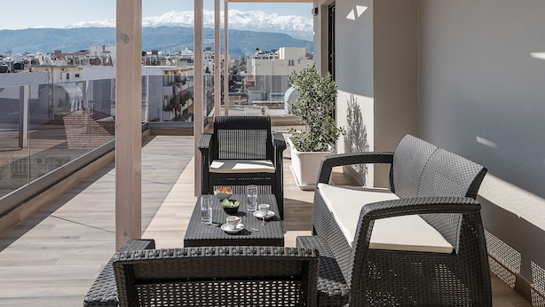 Een balkon met rieten meubels, een tafel en een plant in pot.