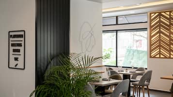Un comedor moderno con un gran ventanal, una obra de arte abstracto colgada en la pared, y un cartel que indica una sala de juegos y reuniones.