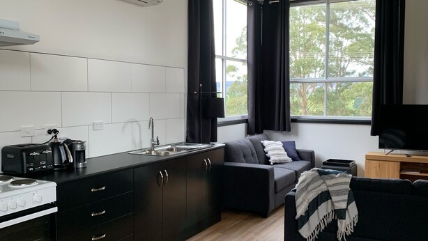 A modern kitchen with a built-in stove, a sink, and a window with curtains.