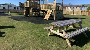 Un parque infantil con una estructura de madera para escalar y una mesa de picnic.