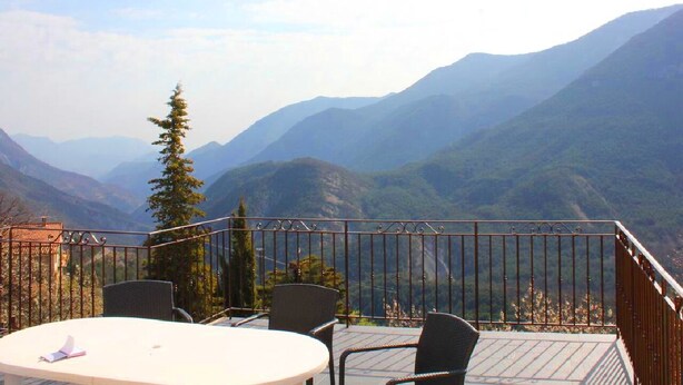 Une terrasse avec une table et des chaises donnant sur un paysage montagneux.