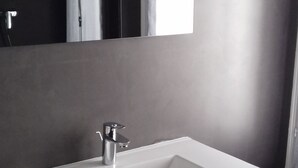 Une salle de bain avec un lavabo blanc, un meuble-lavabo en bois foncé et un miroir au-dessus.