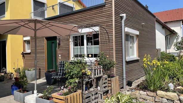 A residential building with a balcony, outdoor seating, and potted plants. - Cozy barrier-free FEWO in new building directly between vineyards and the Main river (Segnitz)
