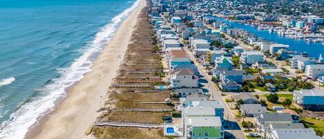 An aerial view of a coastal town with a beach, residential buildings, and a marina.