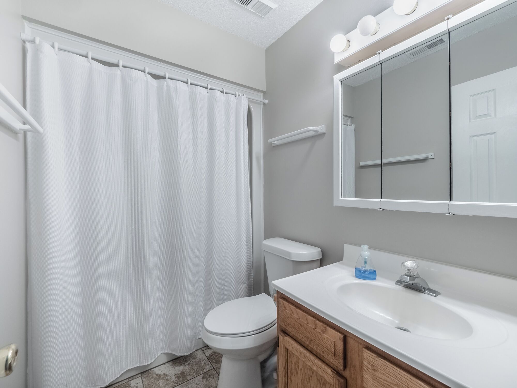 A bathroom with a white toilet, a white sink, a mirror, and a shower curtain.