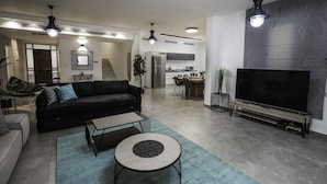 A modern living room with a black sofa, a coffee table, and a TV on a wooden stand. - YalaRent Caesar's Villa - Families only (Eilat)