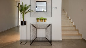 A modern interior with a staircase, a wall-mounted mirror, a potted plant, and a geometric side table. - YalaRent Caesar's Villa - Families only (Eilat)