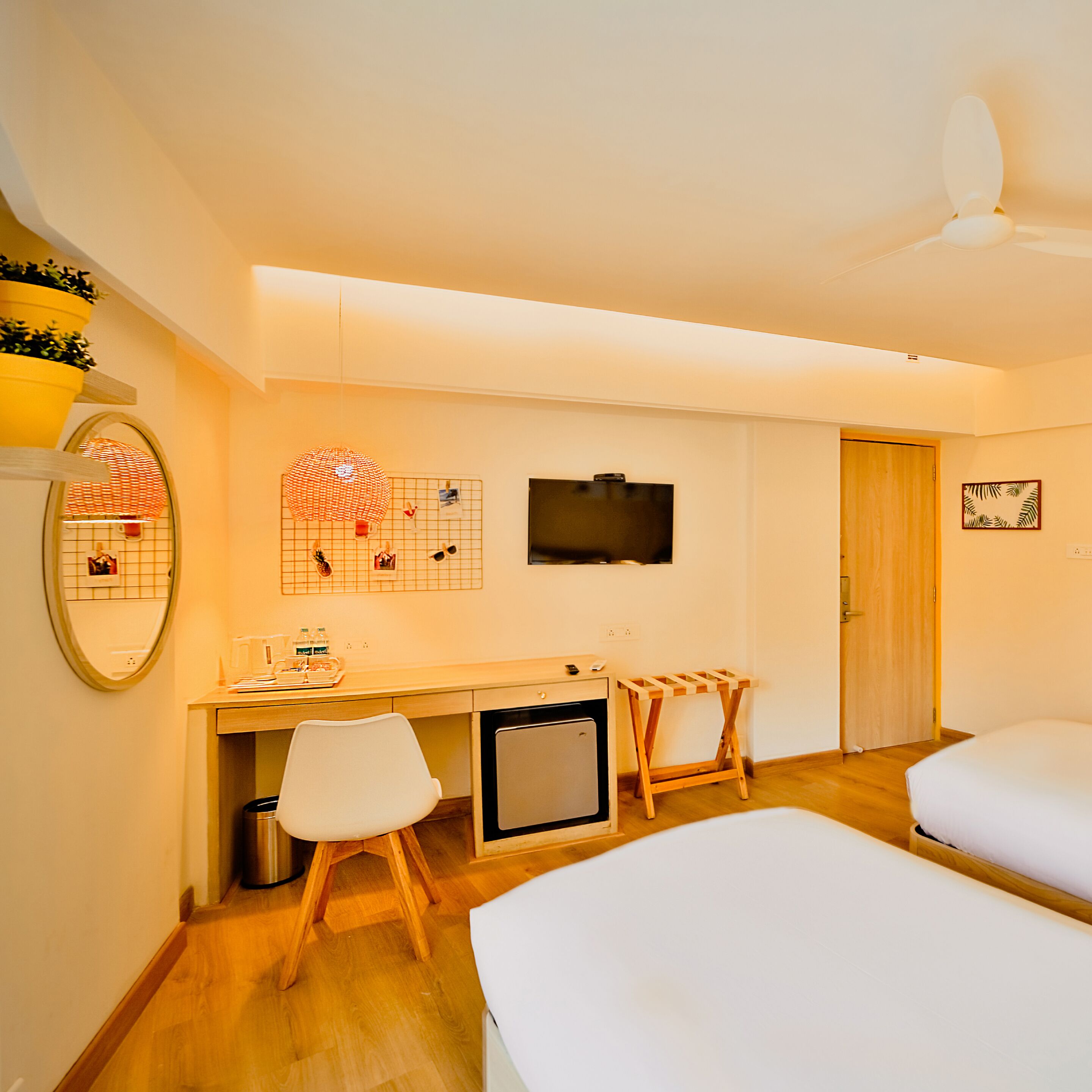 Una habitación de hotel con escritorio, televisor, cama y un refrigerador pequeño.