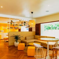 Uma sala de estar moderna com sofá, pufes, uma mesa redonda e um vaso com planta.