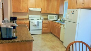 Una cocina con armarios de madera, estufa, microondas y refrigerador.