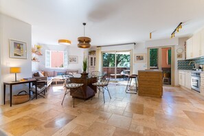 Amplia sala de estar con mesa de comedor, sillas, sofá y zona de cocina con armarios y encimera.
