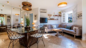 Ein modernes Wohnzimmer mit einem Glastisch, Korbstühlen, einer Couch und einem Fernseher.