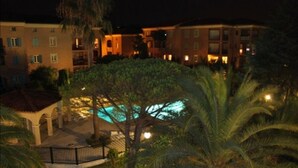 Ein Hotel mit Swimmingpool, umgeben von Palmen und einem eingezäunten Innenhof.
