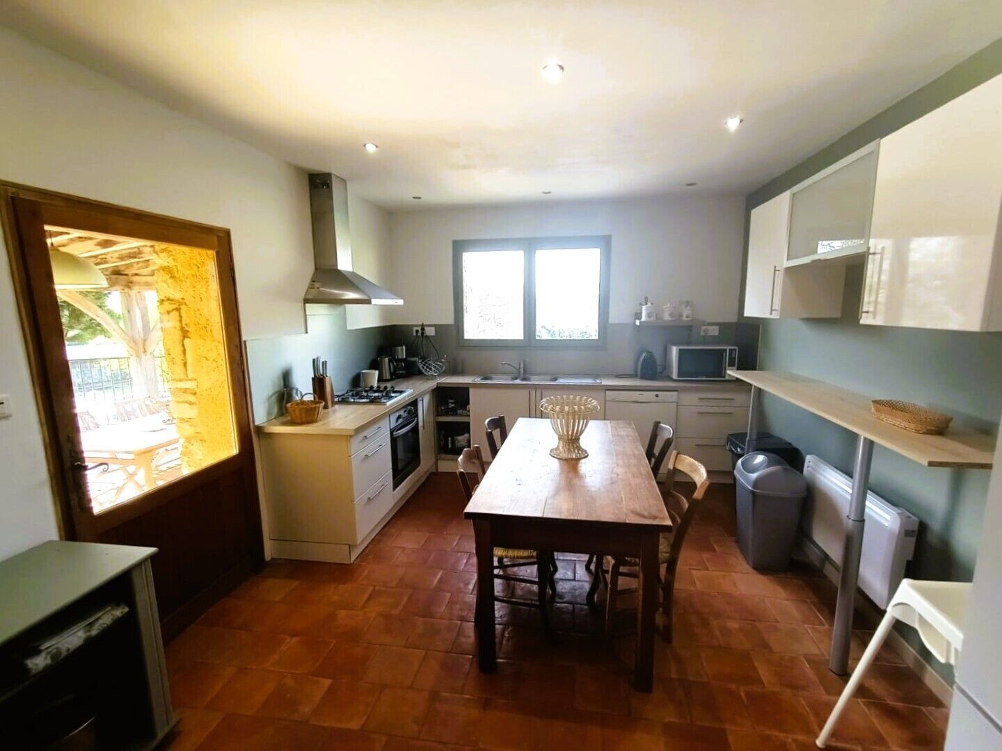 Een kleine keuken met een eettafel, een fornuis en een magnetron.