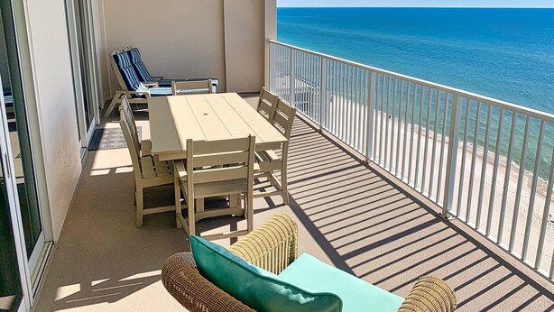 Un balcone con tavolo e sedie, vista sulla spiaggia.