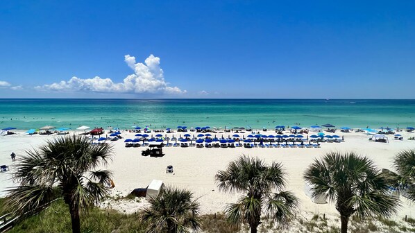 Relax on the beach with shade from the numerous umbrellas and palm trees.