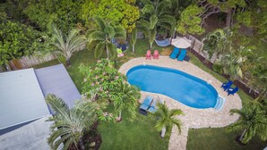 An aerial view of a backyard with a swimming pool, surrounded by palm trees and a wooden deck. - Charming Oasis with a Pool (Fort Lauderdale)
