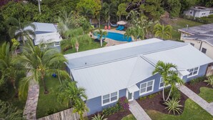 A residential property with a swimming pool, palm trees, and a paved walkway. - Charming Oasis with a Pool (Fort Lauderdale)