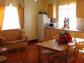 Uma cozinha compacta com geladeira, micro-ondas e uma mesa de jantar com cadeiras.
