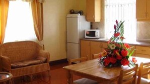 A compact kitchen with a refrigerator, microwave, and a dining table with chairs.