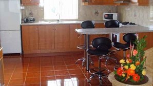 A kitchen with wooden cabinets, a white refrigerator, a microwave, and a dining area with a table and chairs.