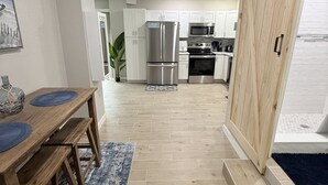 Une cuisine moderne avec des meubles blancs, des appareils en acier inoxydable et une table à manger en bois agrémentée de sets de table bleus.