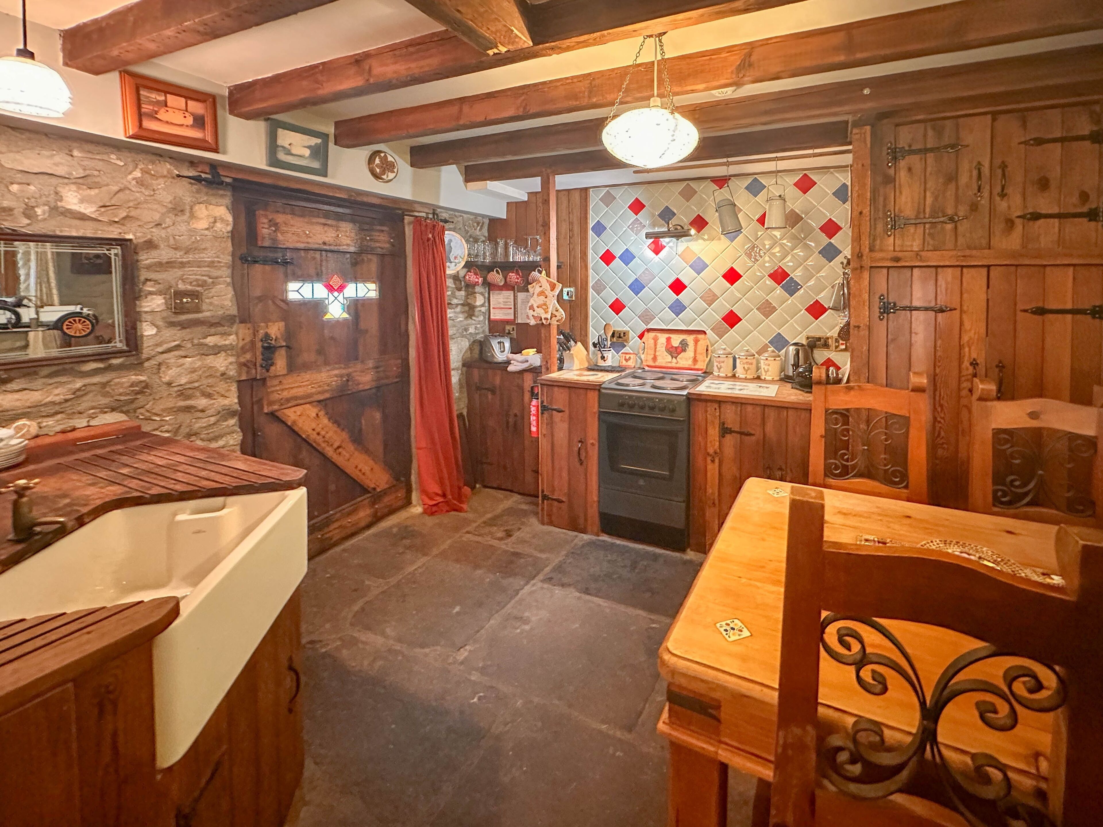 A rustic kitchen with wooden cabinets, a stone wall, and a tiled backsplash.