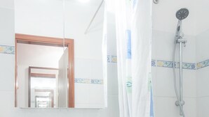 Ein Badezimmer mit einem weißen Waschbecken, einem Spiegel, einer Dusche und einem Duschvorhang mit einem Seepferdchenmuster.