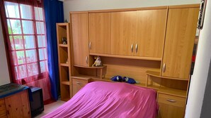A bedroom with a bed, wooden wardrobe, and a television. - Casa Familia (La Orotava)