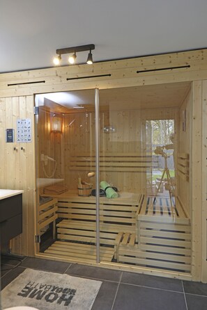 A sauna room with wooden walls, a glass door, and a bench. - Relax House, with an outdoor hot tub and sauna for exclusive use, 300 meters from the lake (Göhren-Lebbin)