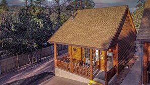A wooden cabin with a porch, a covered outdoor seating area, and a view of the surrounding forest. - 6 Cabins with Kitchens+Gameroom&Playground (Payson)