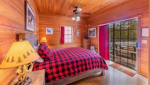 A wooden cabin room with a bed, a table with a lamp, and a window with curtains. - 6 Cabins with Kitchens+Gameroom&Playground (Payson)