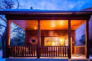 Situated in a wooded area, the Black Bear Cabin features a simple, rustic design with a covered porch.