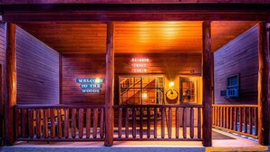 A wooden cabin with a sign reading "Welcome to the Woods" and "Rainbow Trout Cabin".