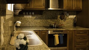 A kitchen with granite countertops, wooden cabinets, a stainless steel sink, and a built-in oven. - Villa Eros (Corfu)