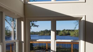 Ein Zimmer mit Blick auf einen See und einer Holzterrasse.