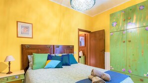 A bedroom with a bed, a nightstand, a green wardrobe, and a framed picture on the wall. - Country House Donoratico - Cottage Bougainville (Donoratico)