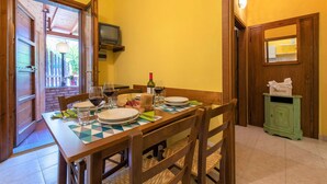 A dining area with a wooden table set for four, a television above it, and a green cabinet with a tissue box. - Country House Donoratico - Cottage Bougainville (Donoratico)