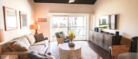 A living room with a sofa, armchairs, a coffee table, a TV, and a ceiling fan.